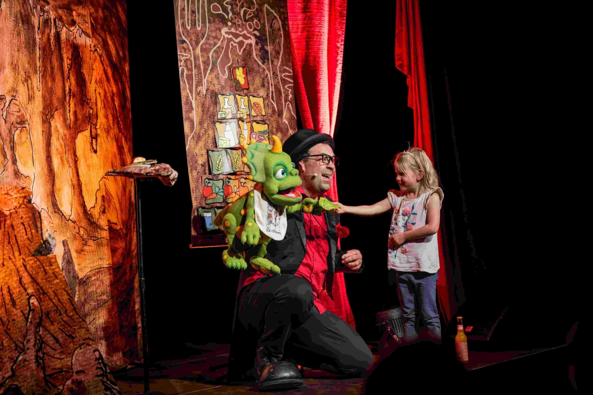 Kind füttert Dino-Baby vor Ernährungspyramide (Szenenfoto Ernährungstheater ZaPPaloTT)